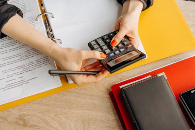 Dosar cu documente și un calculator pe un birou, pregătite pentru o cerere de finanțare