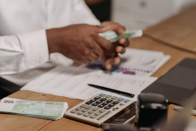 Laptop și foi cu calcule financiare pe un birou, folosite pentru compararea unor variante de finanțare